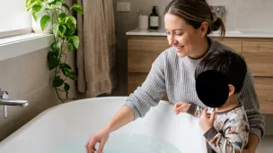 parent preparing a warm sensory bath for an autistic child using evidence-based bath products.